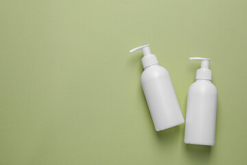 Different cleansers on olive background, flat lay with space for text. Cosmetic product