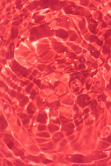 Redwater with ripples on the surface. Defocus blurred transparent orange colored clear calm water surface texture with splashes and bubbles. Water waves with shining pattern texture background.