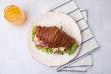 Tasty croissant with brie cheese, ham and bacon on white tiled table, flat lay