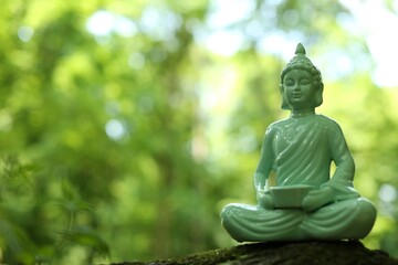 Decorative Buddha statue on blurred background. Space for text