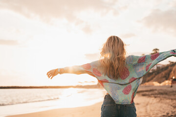 One happy beautiful woman walking on the sand of the beach enjoying and having fun at the sunset of...
