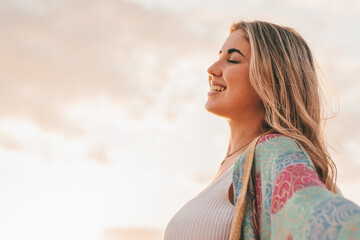Portrait of one young woman at the beach with openened arms enjoying free time and freedom outdoors. Having fun relaxing and living happy moments..