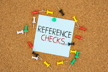 Reference checks text on light blue post-it paper pinned on bulletin cork board surrounding by...