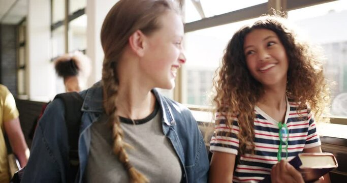Friendship, talking and students walking in the hallway together to bond or discuss academic work. Happy, diversity and teenage girl friends laughing and speaking in the corridor of their high school