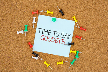 Time to say goodbye text on light blue post-it paper pinned on bulletin cork board surrounding by...