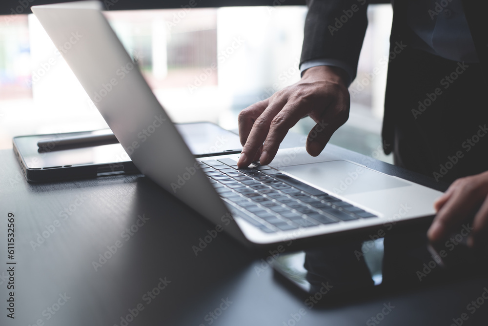 Wall mural closeup of businessman working on laptop computer with digital tablet and mobile phone on office tab