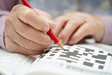 Asian elderly woman playing sudoku puzzle game to practice brain training for dementia prevention,...