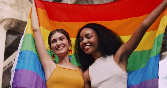 A lesbian couple waves a rainbow flag, a symbol of homosexuality, during a pride parade.