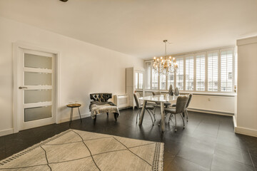 a living room with white walls and black flooring in the center of the room is a dining table, two chairs and a