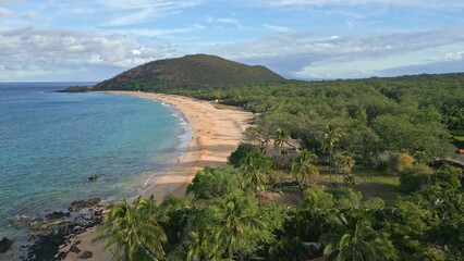 Aerial drone view along the coast approaching Makena Cove and rising up to Makena Beach in Kihei, on the island of Maui in Hawaii. Shot during spring, April, 2023 during early morning, flying forward 