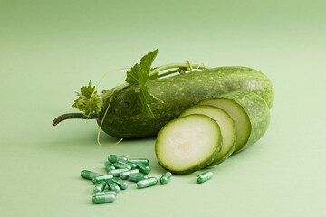 Against the green background, fresh winter melon, slices and leaf with some vitamin capsules....