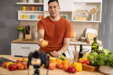 Fototapeta premium A male social media influencer creates videos, shares instructions for making fruit salad online, expands his subscriber and advertising-generating audience. Start-up options for new small businesses