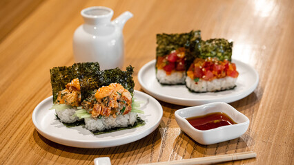 Japanese opened hand sushi rolls with different fish and sauce on table