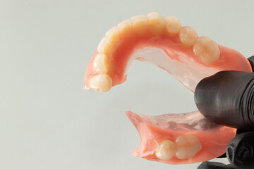 Woman holding a broken lower complete denture. Selective focus.