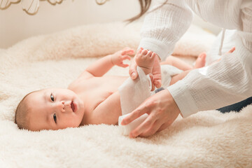 ベッドで寝る赤ちゃんに包帯を巻くママ・親子・母子
