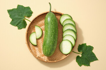 Against the beige background, fresh winter melon, slices and green leaves placed on bamboo basket. Minimal concept with top view, flat lay for advertising product of winter melon ingredient
