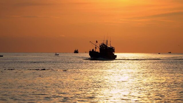 Sunrise landscape at sea with colorful cloudy sky, along with silhouettes of fishing boats of fishermen running back and forth. Video natural landscape sunset and sunrise.