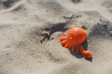 Close-up of an orange childrens sand mold lying in sand on a beach