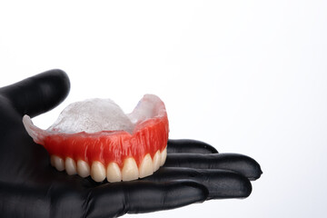 Waxed upper denture base on woman hand. Test base with artificial teeth ready to acrylization.