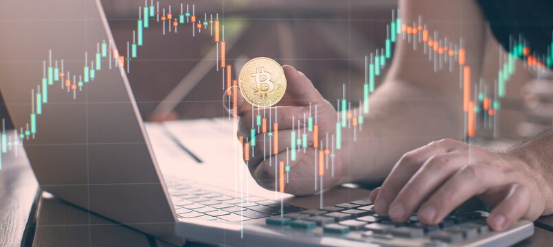 Laptop with chart and bitcoin in hands. Cryptocurrency gold coin, stock exchange graph background.
