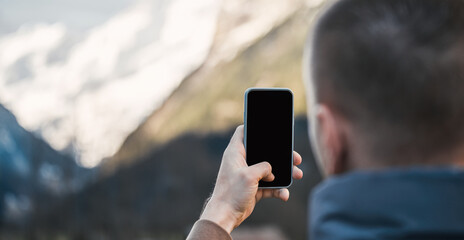 Man taking photos in beautiful outdoors. Traveling in the Alps. Mobile phone camera mockup