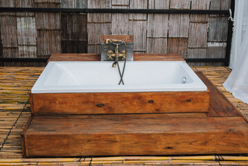 Modern and vintage outdoor jacuzzi on a wooden deck in the middle forest.