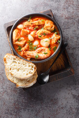 Brudet or Brodetto tasty stew of fish, seafood such as shrimps, scallops, calamari, mussels close-up in a bowl on the table. Vertical top view from above