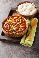 Rajma Masala is a delicious gravy made by cooking red beans with onion, tomatoes and basic spices served with rice close-up on a wooden tray on the table. Vertical