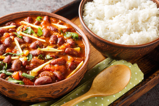 Rajma Or Razma is a popular North Indian Food, consisting of cooked red kidney beans in a thick gravy with spices served with rice close-up on a wooden tray on the table. Horizontal