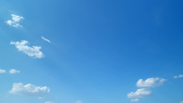 Clouds running across the blue sky. White puffy and fluffy clouds on blue sky. Timelapse.