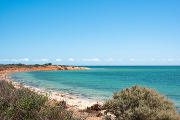 view of the sea from the beach, red orange sand and turquoise water. Shark bay Australia
