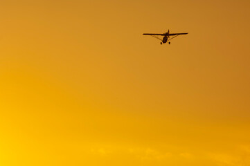 Ultralight plane silhouette in orange sky at sunset