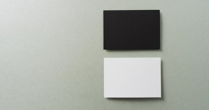 Close up of two stacks of black and white business cards on grey background, copy space, slow motion