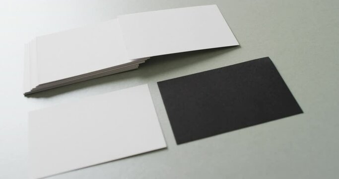 Close up of blank white and black business cards on grey background, copy space, slow motion