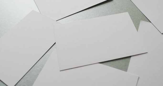 Close up of white business cards scattered on grey background, copy space, slow motion