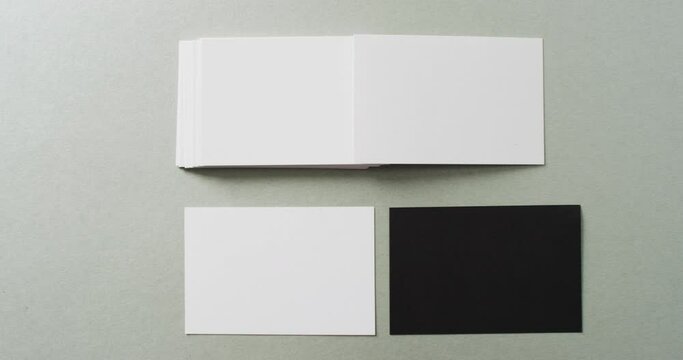 Overhead view of blank white and black business cards on grey background, copy space, slow motion
