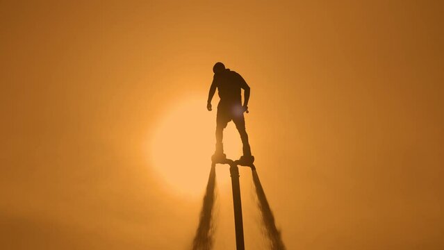Silhouette of a flyboarder on the background of the sunset sky. Athlete flyboarder on the background of the sun