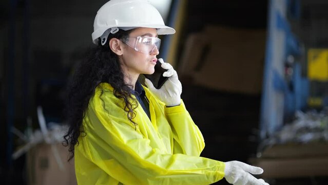 Black-haired inspector talks on phone with director of waste sorting plant. Female manager controls working process at trash processing factory