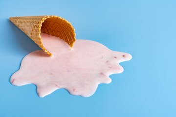 Strawberry ice cream melting and spilling from the waffle cone