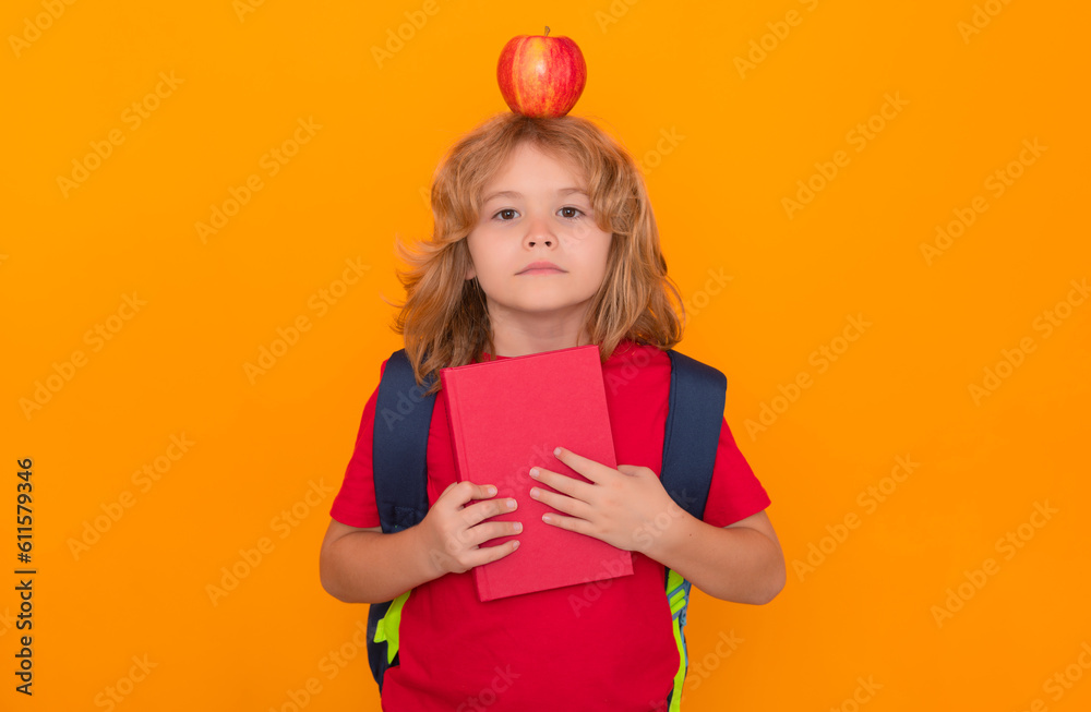 Poster apple on head, idea concept. child from elementary school with book and apple isolated on yellow bac