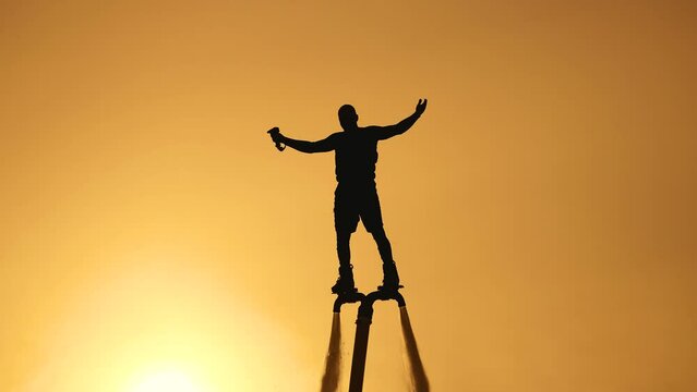 Silhouette of a flyboarder on the background of the sunset sky. Athlete flyboarder on the background of the sun