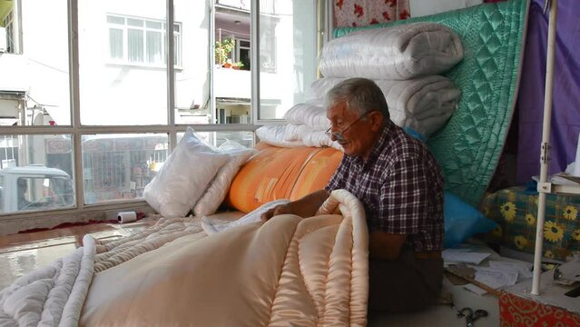 old man sewing a quilt with his hands
