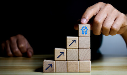 Businessman putting virtual quality assurance hands and screen-printed arrows on wooden cubes to increase product quality, guarantee and service concept, iso quality assurance