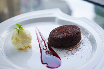molten chocolate cake and vanilla ice cream ball with almond slices on white plate