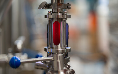 Metallic detail of soft drink factory with red drink. Brewery