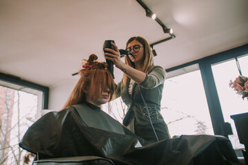 Hairdresser blow drying her clients hair