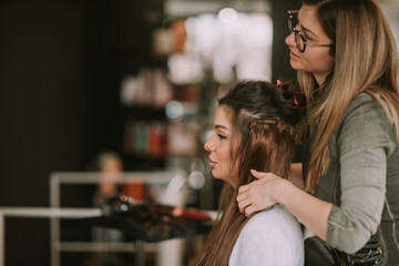 Brunette hair stylist making her client hair 