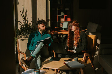 Lovely redhead businesswoman talking to her good looking male colleague while working together at the coffee bar
