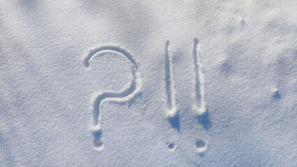 Question mark and exclamation mark on snowy surface close-up. Copy space. Confusion situation