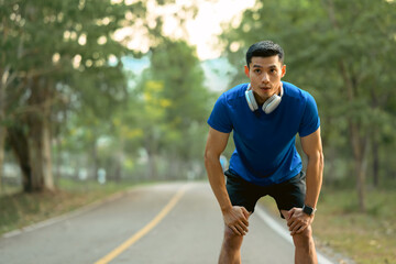Fototapeta premium Image of tired sportsman resting after running at sunny morning. Fitness, training and healthy lifestyle